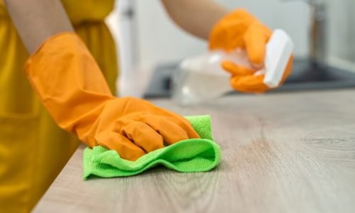 close-up-human-hands-yellow-gloves-with-spray-cleaning-wooden-surface_359031-16558
